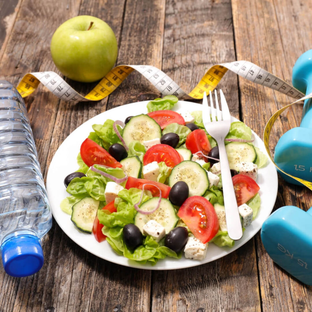 Healthy habits: salad, apple, water bottle, and weights