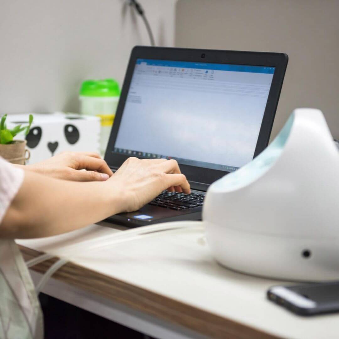 Mom breast pumping while working on a computer at work