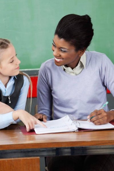 Teacher helping elementary student with data binder