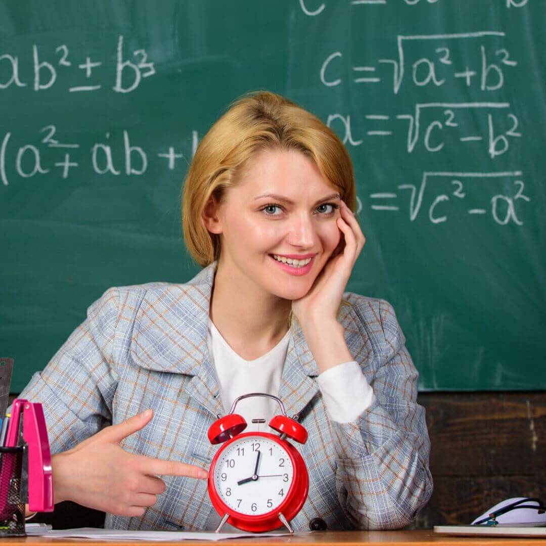 Teacher sitting at a desk with a clock