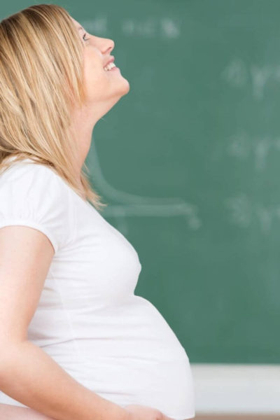 Blonde pregnant teacher in front of blackboard
