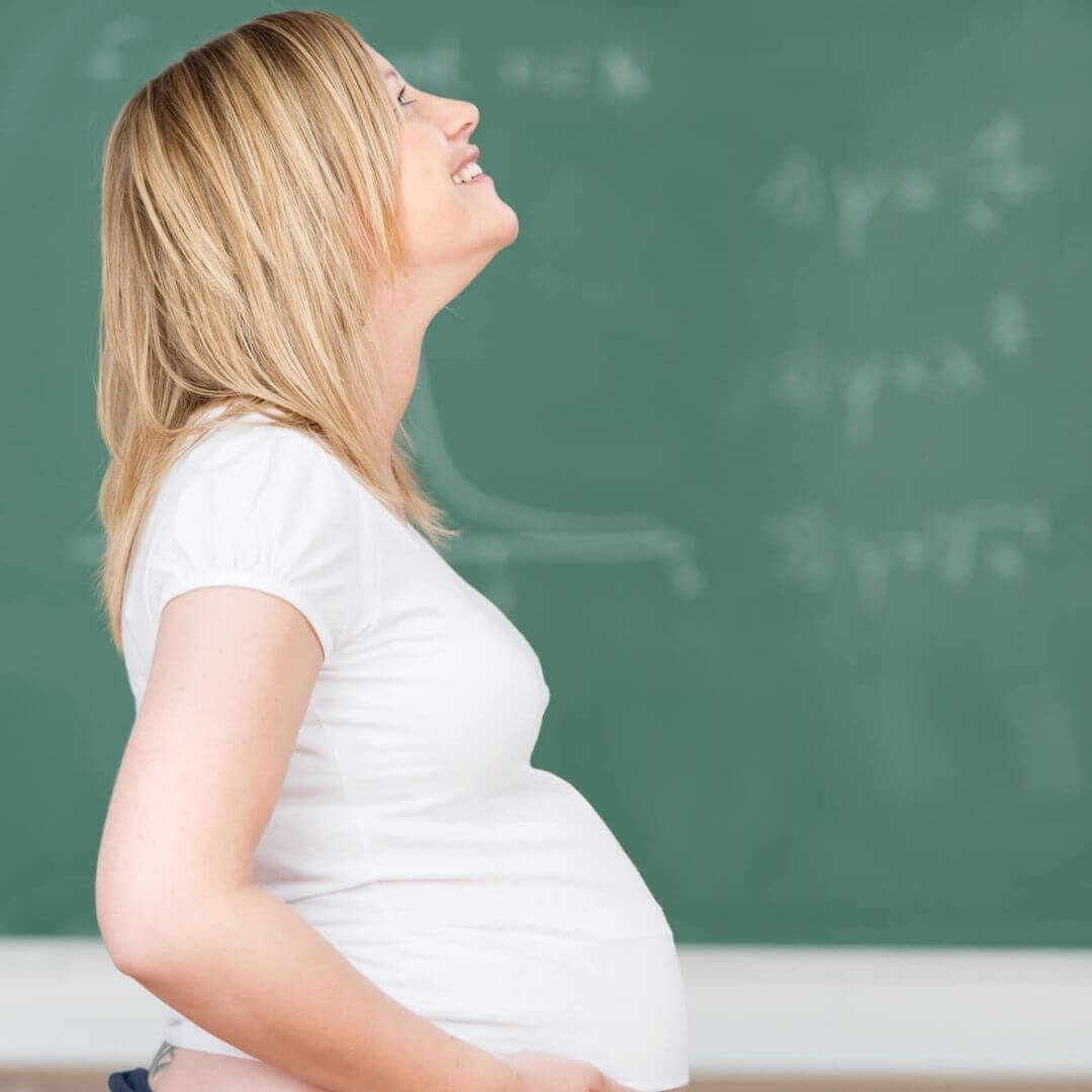 Blonde pregnant teacher in front of blackboard